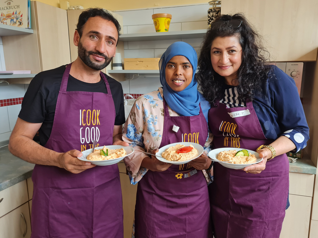 Über den Tellerrand Hamburg e. V., 3 aus dem Team zeigen 3 Teller mit Essen